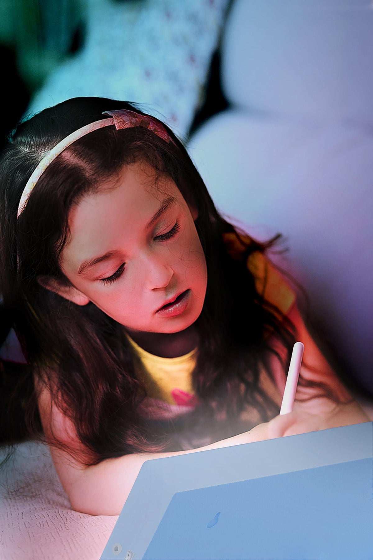 Child using a blue LED light box while writing with a pen