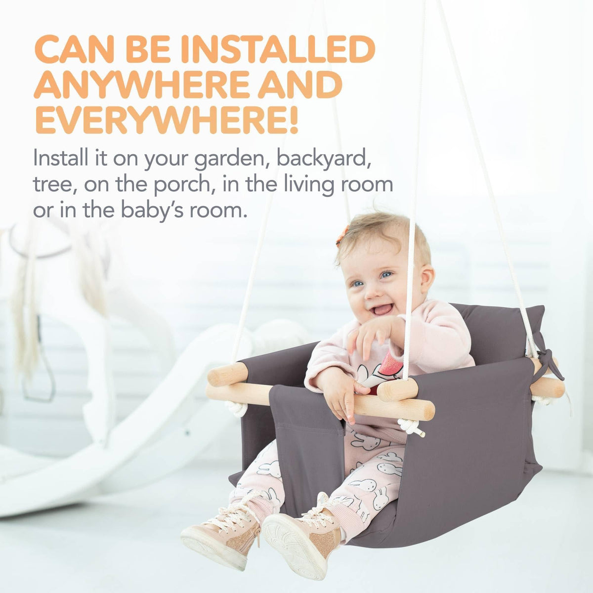 Dark gray baby hanging swing chair with wooden dowels, baby seated and smiling