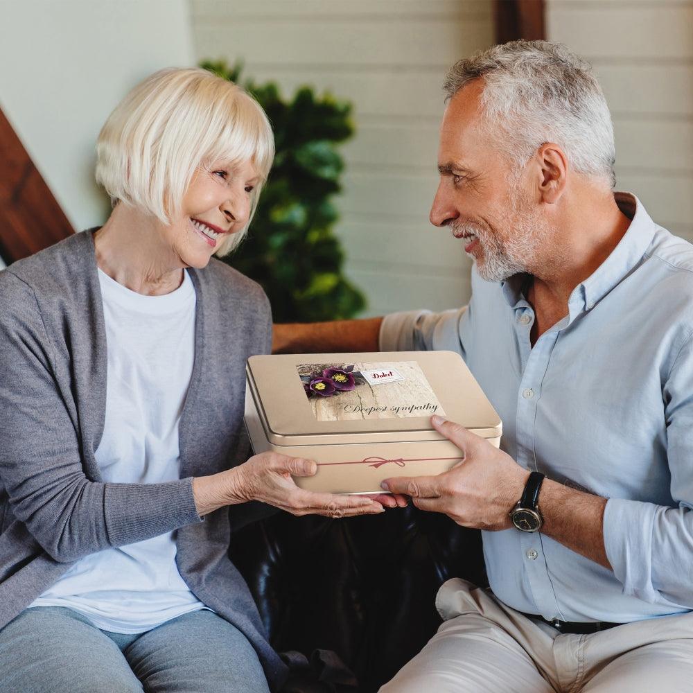 Deluxe Honey & Pastry gift tin held by an older couple together