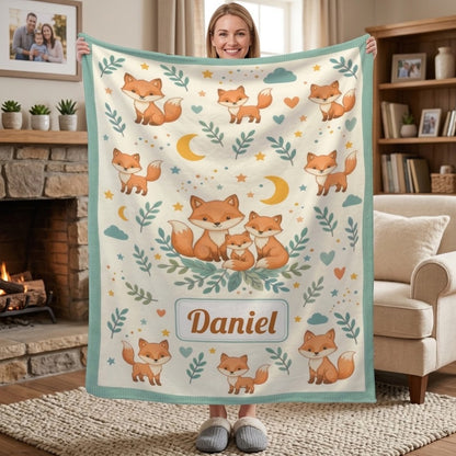 Fox blanket held up showing woodland foxes, stars and leaves with teal border and Daniel.