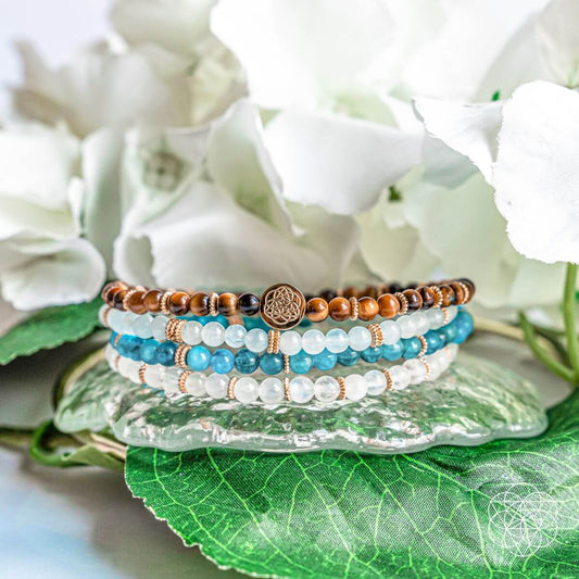 Four beaded bracelets with brown tiger’s eye, blue stones, and gold round charm