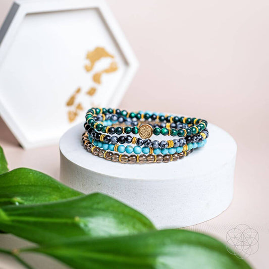 Turquoise beaded energy bracelet stack with gold-tone accents and charm centerpiece