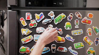 Hand arranging colorful foam vehicle and profession magnets on a stainless fridge
