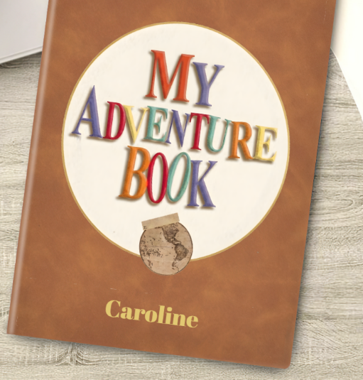 Close-up brown notebook cover with “My Adventure Book” emblem and name “Caroline”