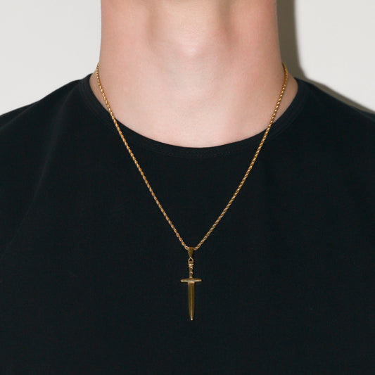 Gold dagger pendant necklace worn at the collar on a dark crewneck shirt
