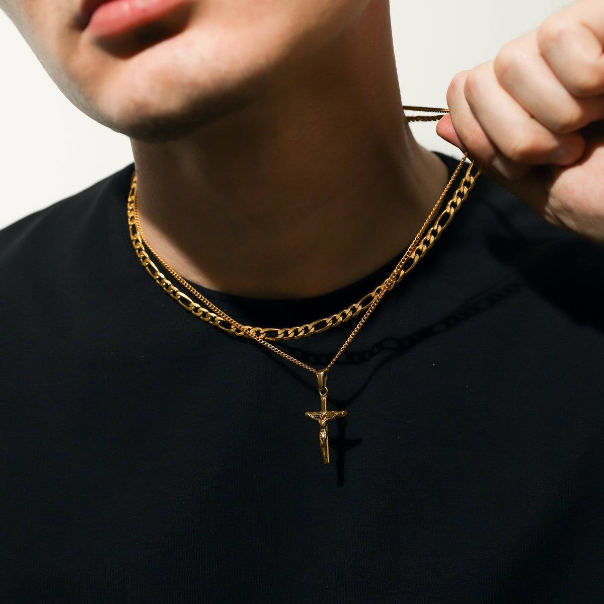 Gold figaro chain with crucifix pendant, close-up on neck and pendant