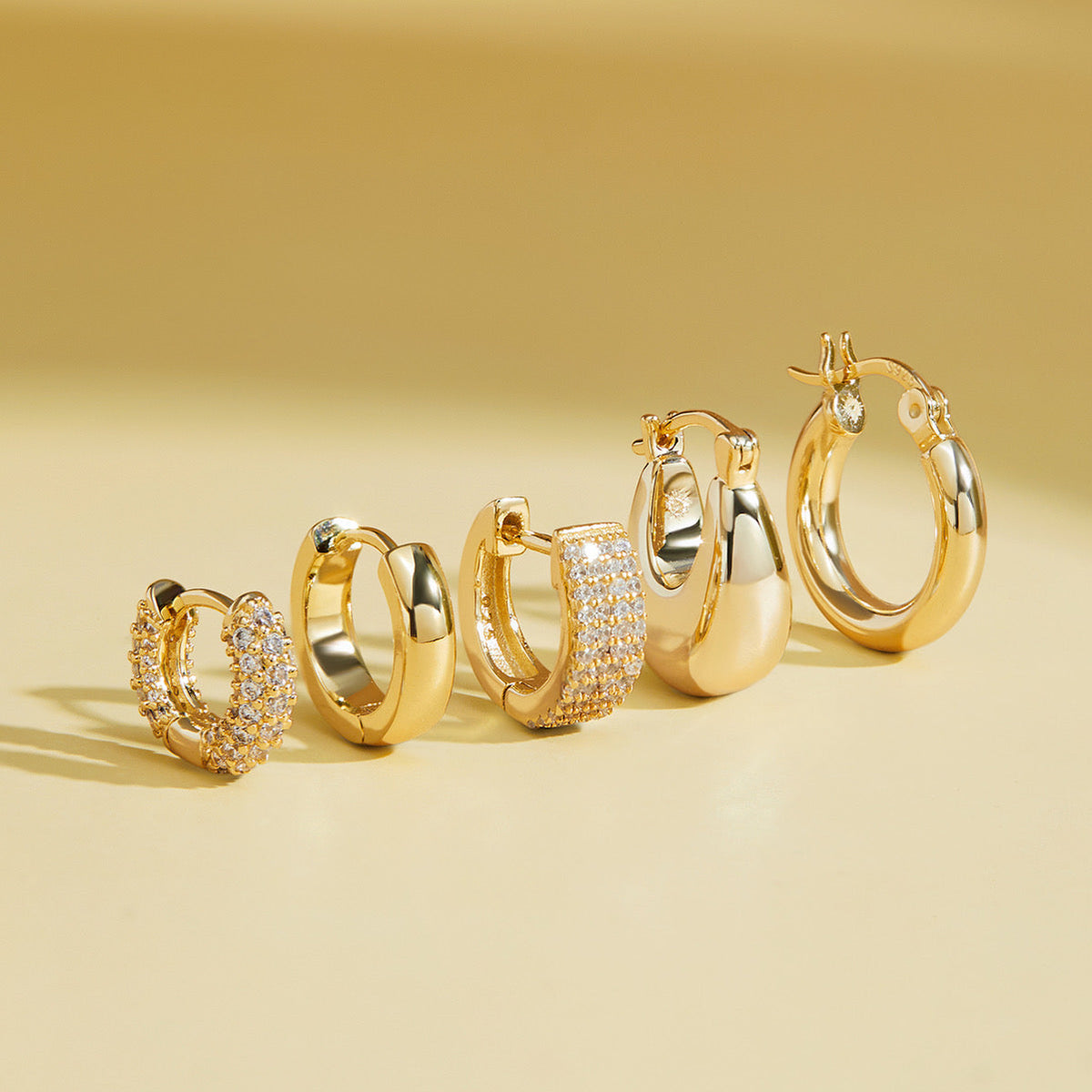 Pave huggie hoop earrings in gold and silver finishes, shown grouped together