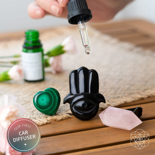 Car diffuser set with black hand, green heart, pink wand as oil drops from dropper