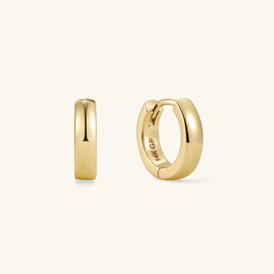 Bold gold huggie hoop earrings with smooth rounded profile