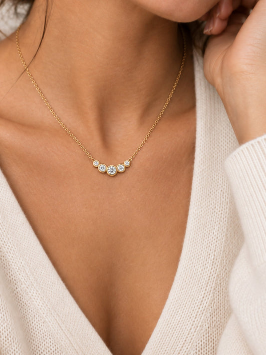 Gold diamond cluster necklace resting at collarbone on a gold chain