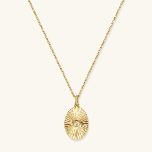 Gold oval sunburst pendant necklace on a fine chain with small center gem
