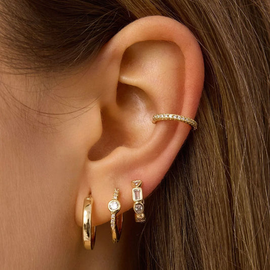 Gold-tone hoop earrings on ear, including stone-studded bezel and plain hoops