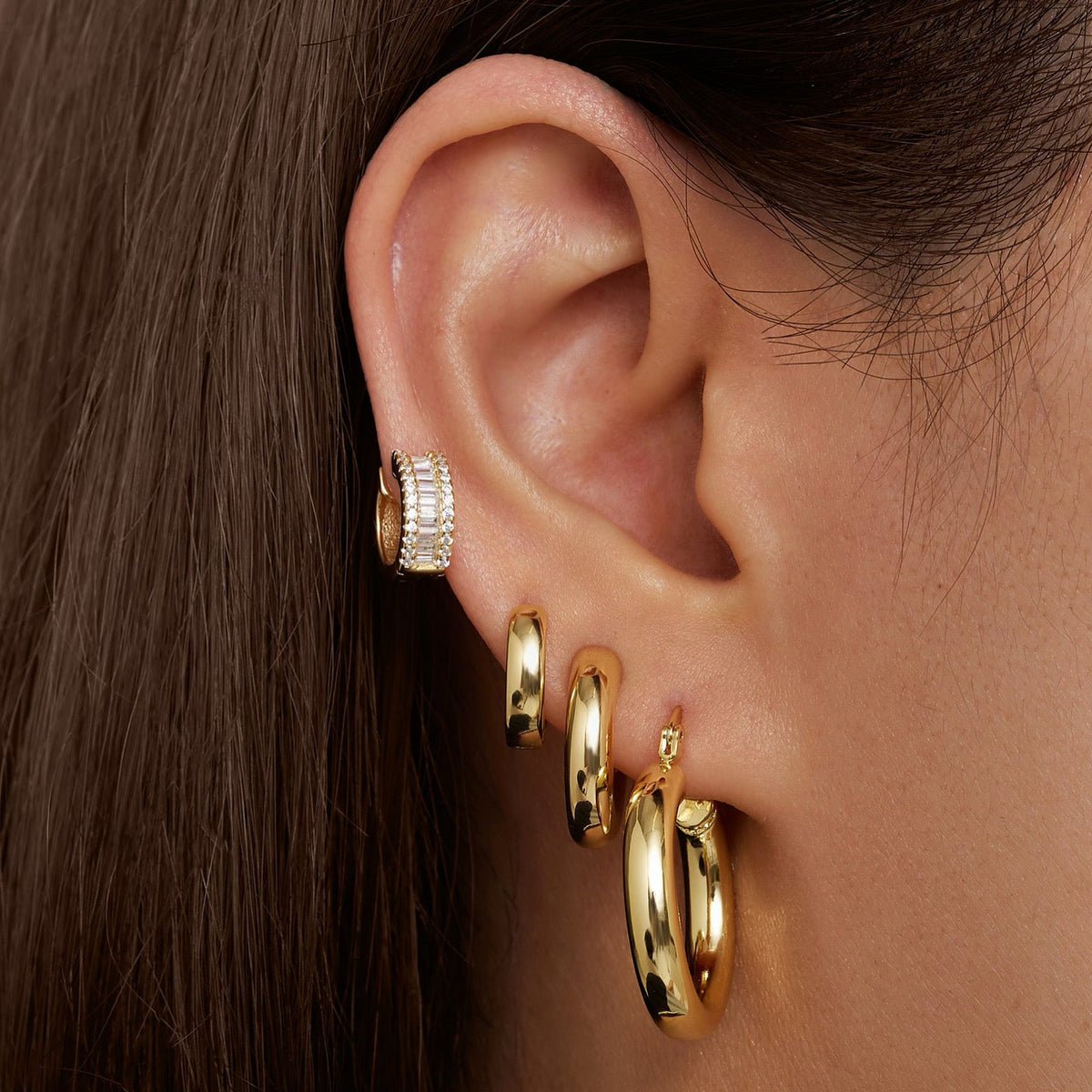 Gold-tone baguette hoop earring worn with matching hoop, stone row detail