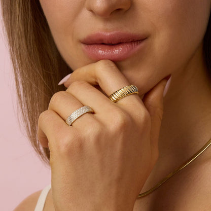 Pave cigar band ring on finger beside a gold ribbed ring