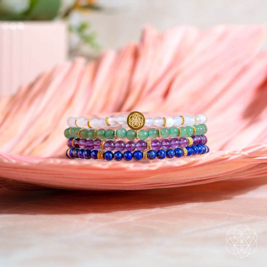 Set of 4 beaded charm bracelets with blue, purple, green, and gold accents