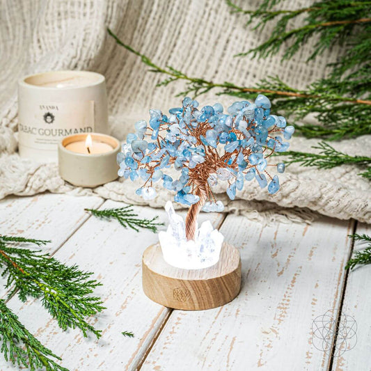 Blue crystal tree lamp with copper branches in a wooden round base, lit crystals