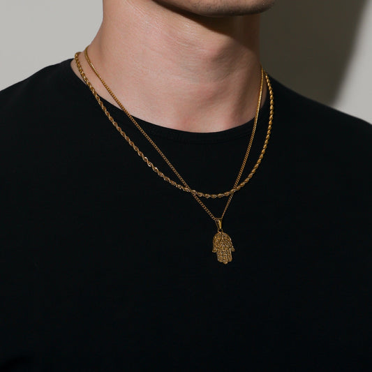Gold hamsa pendant necklace set with two layered chains on a model’s neck