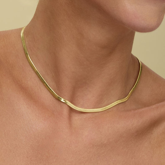 Gold herringbone chain necklace, 16-inch length, worn at the neck