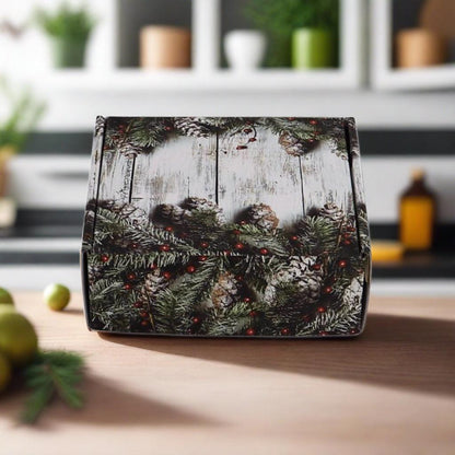 Closed holiday gift box with evergreen wreath and pinecone pattern on the lid.