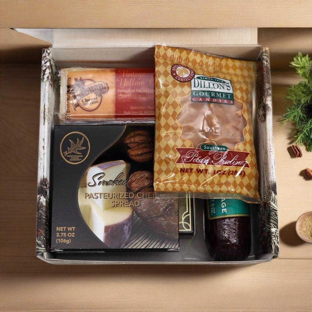 Open holiday gift box with cheese spread and candies, arranged in molded trays.