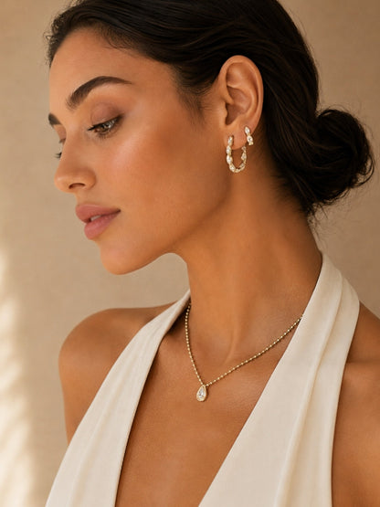 Gold ball-link necklace with teardrop pendant, model side profile with white scarf