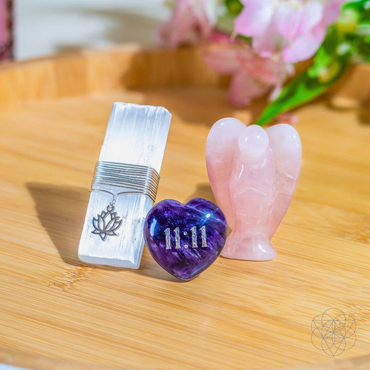 Crystal kit pieces on table: rose quartz angel, amethyst 11:11 heart, and clear metal clip