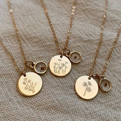 Three gold-tone necklaces with engraved botanical pendants and mustard seed charms