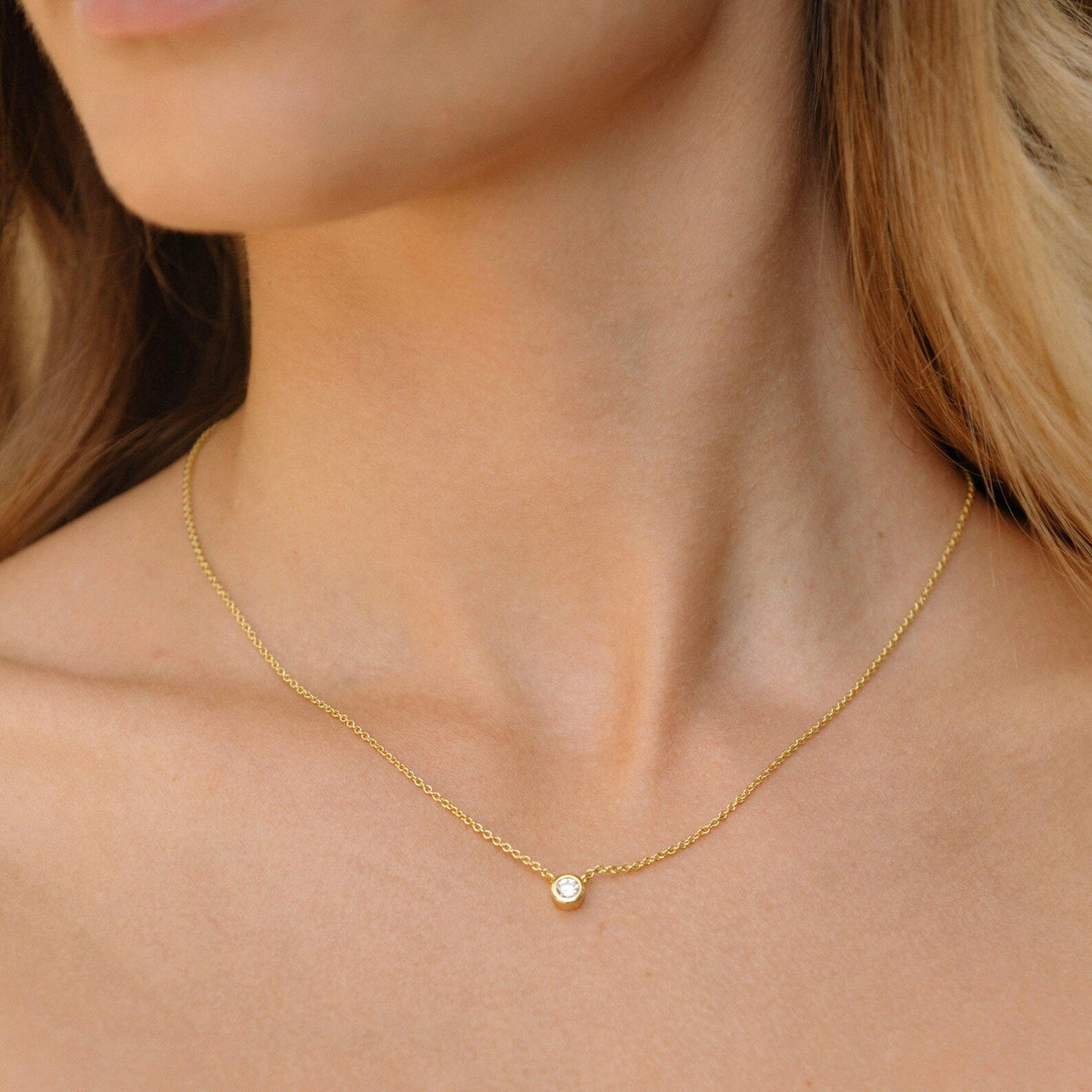 Gold-tone chain necklace with small round bezel-set diamond pendant