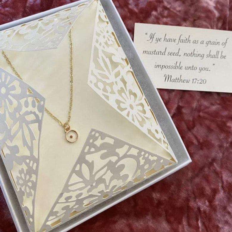 Gold mustard seed necklace displayed in a decorative gift box