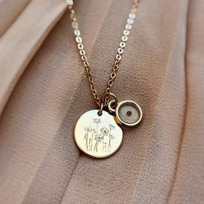 Close-up of engraved poppy pendant and mustard seed charm on a gold-tone chain