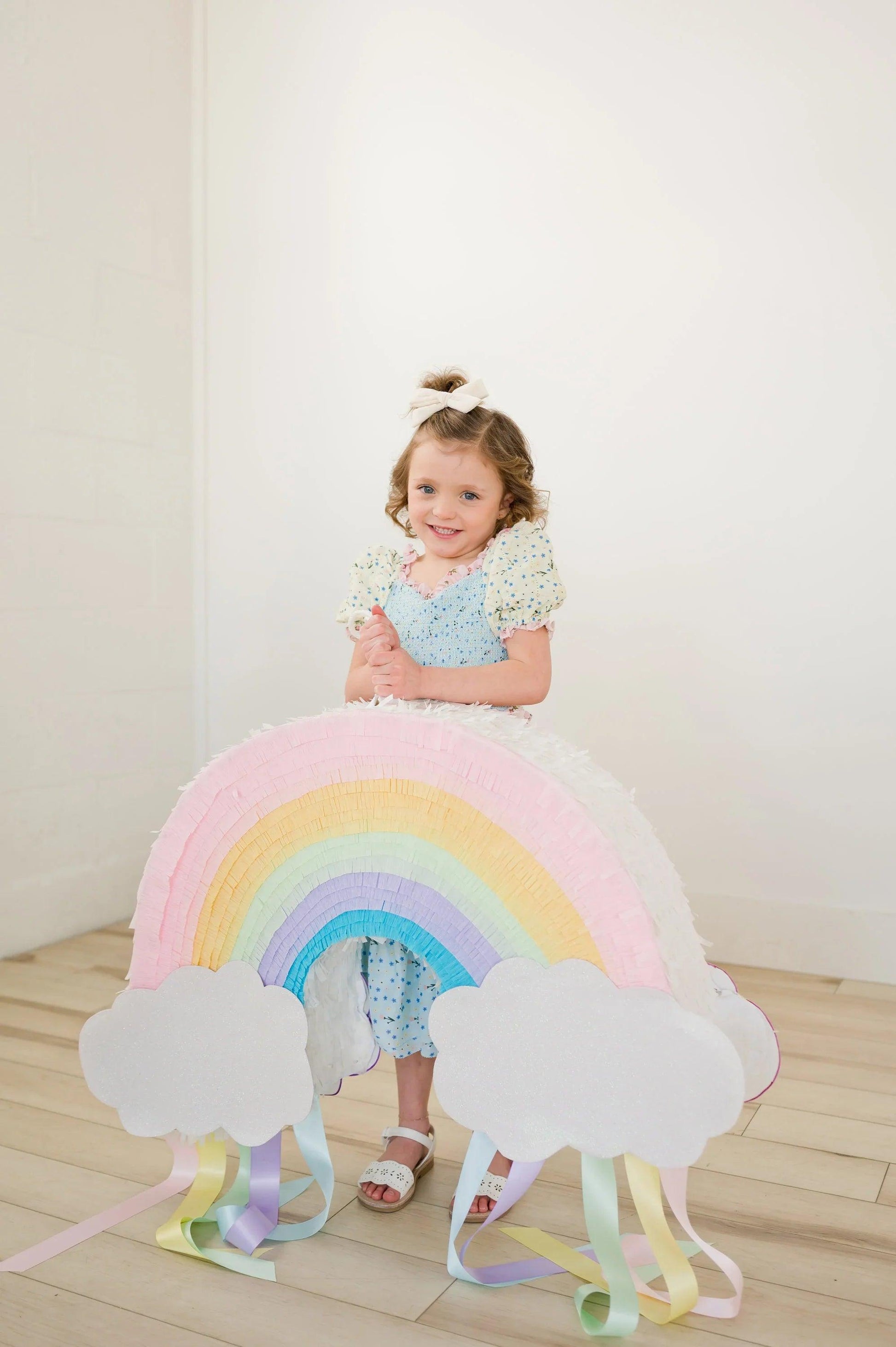 Piñata arcoíris multicolor con nubes blancas y flecos de colores