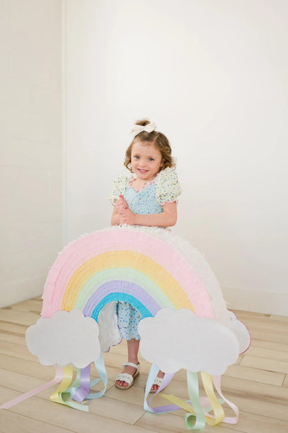 Piñata arcoíris multicolor con nubes blancas y flecos de colores