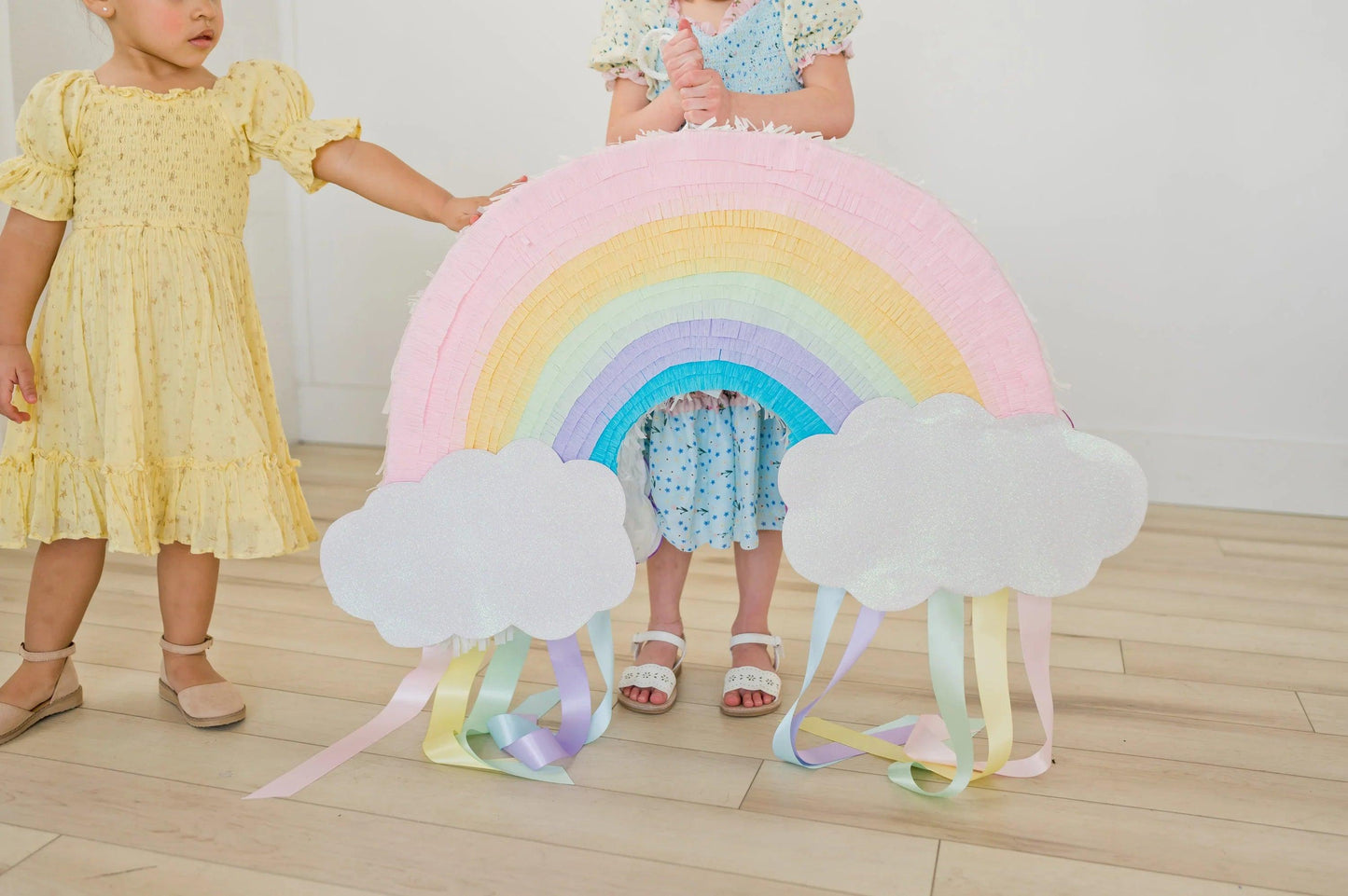 Piñata arcoíris decorativa con nubes grandes y flecos colgantes de colores