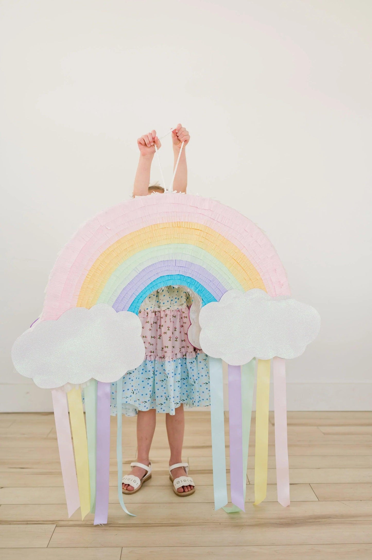 Piñata arcoíris rosa y arcoíris claro con nubes blancas y tiras colgantes
