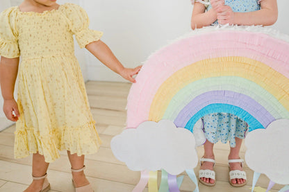 Piñata arcoíris con nubes blancas y flecos de papel de colores