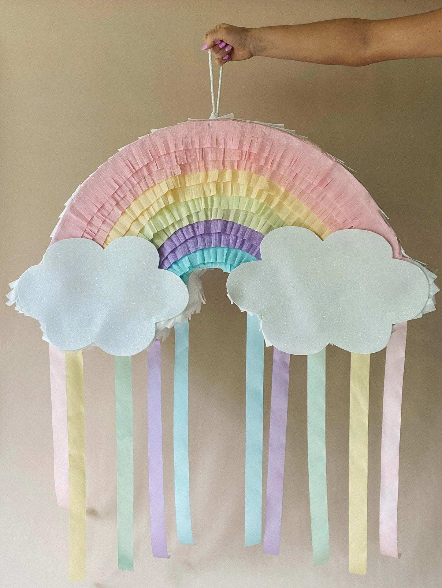 Piñata arcoíris colgante con nubes blancas y tiras multicolor