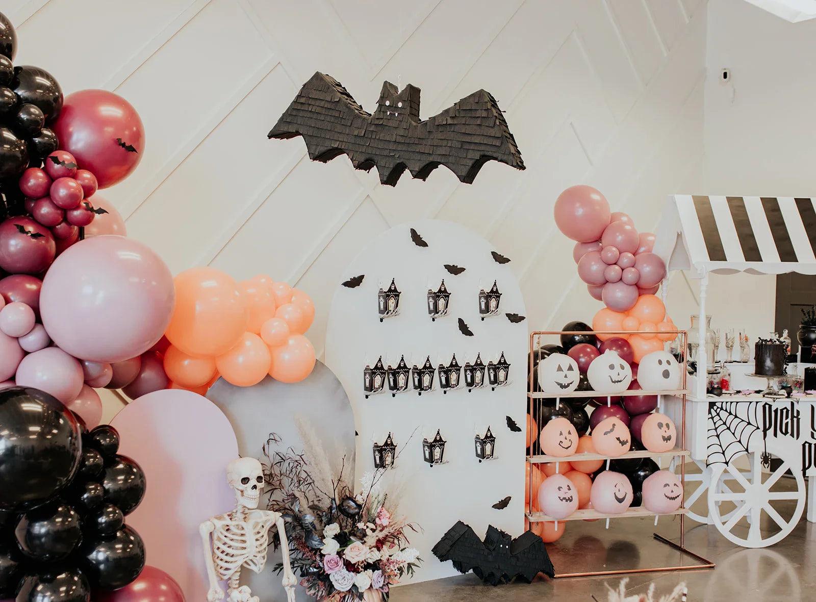 Bat-shaped piñata decoration on the wall, dark gray with hanging string