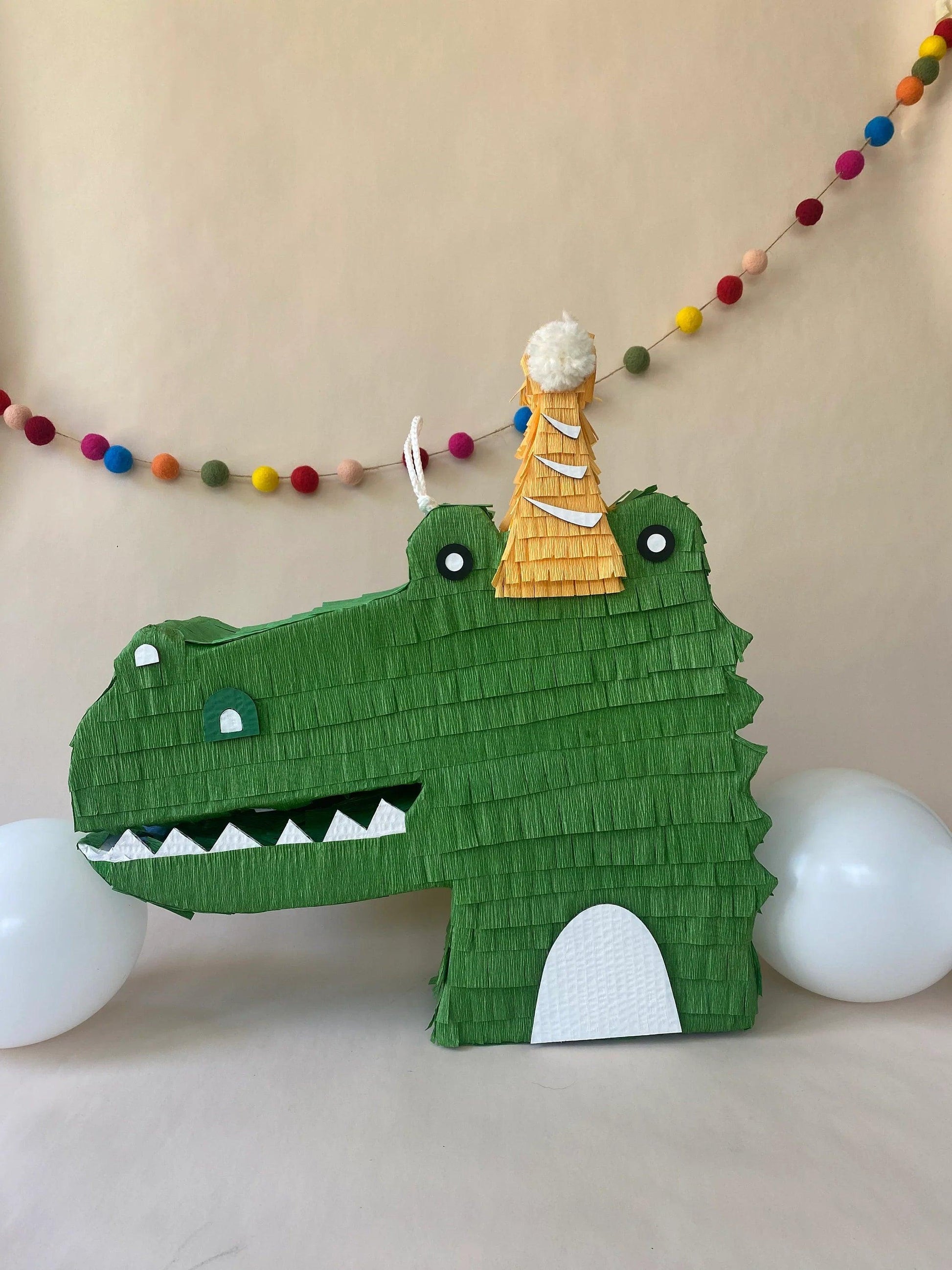 Green handmade alligator piñata candy holder with cream belly and white eyes.
