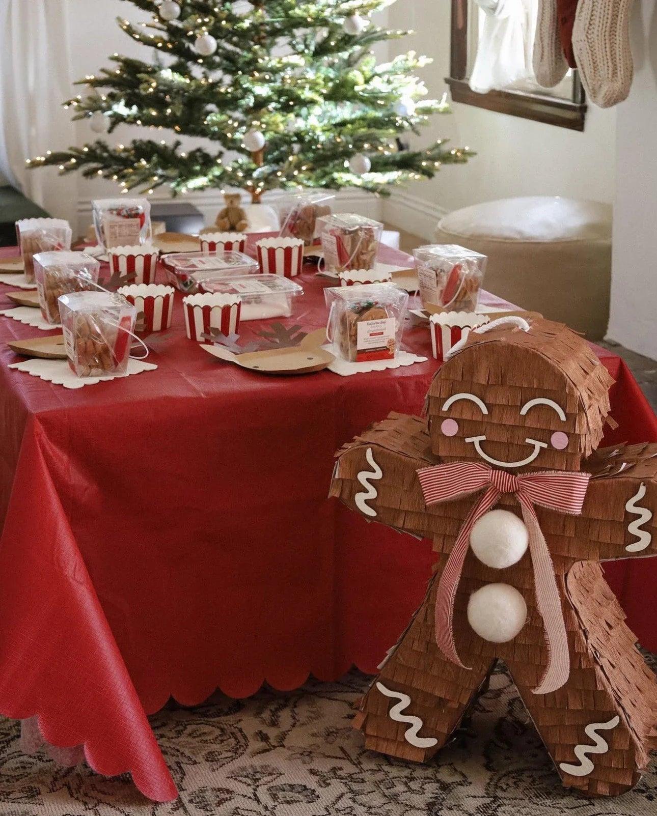 Gingerbread man candy holder piñata on a table, brown with red striped bow