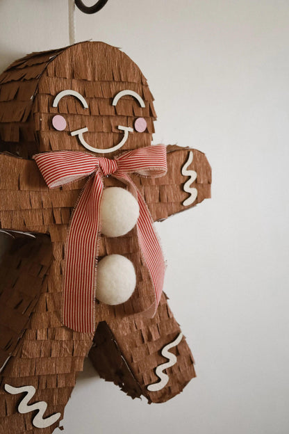 Gingerbread man piñata close-up: red striped bow and three white felt balls