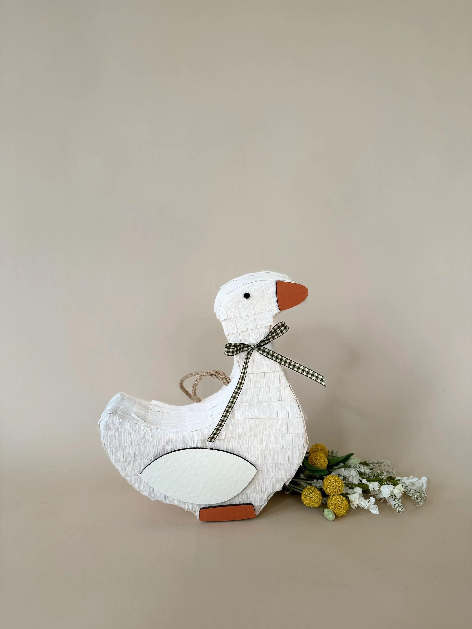 White goose piñata with orange beak and green plaid bow