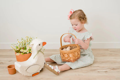 White goose piñata with orange feet accents and green plaid bow at the neck