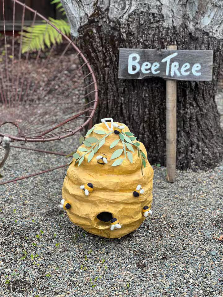 Standing bee hive piñata with leaf crown, plush bees, and round candy opening