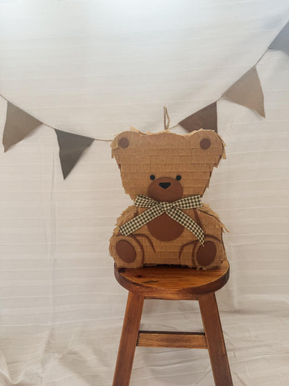 Teddy bear piñata with string loop, tan paper, round ear circles, checkered bow