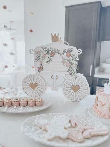 Princess carriage piñata with crown, floral frame, and heart wheels