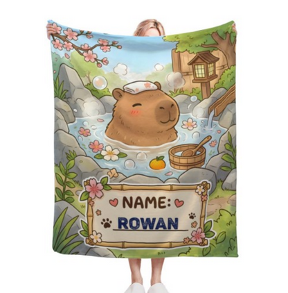 Personalized capybara hot spring blanket with custom name on bamboo sign, kawaii Japanese onsen design with cherry blossoms