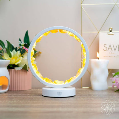 White citrine manifestation lamp with glowing amber ring on a tabletop