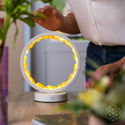 Citrine manifestation lamp with illuminated gold ring in front of seated person