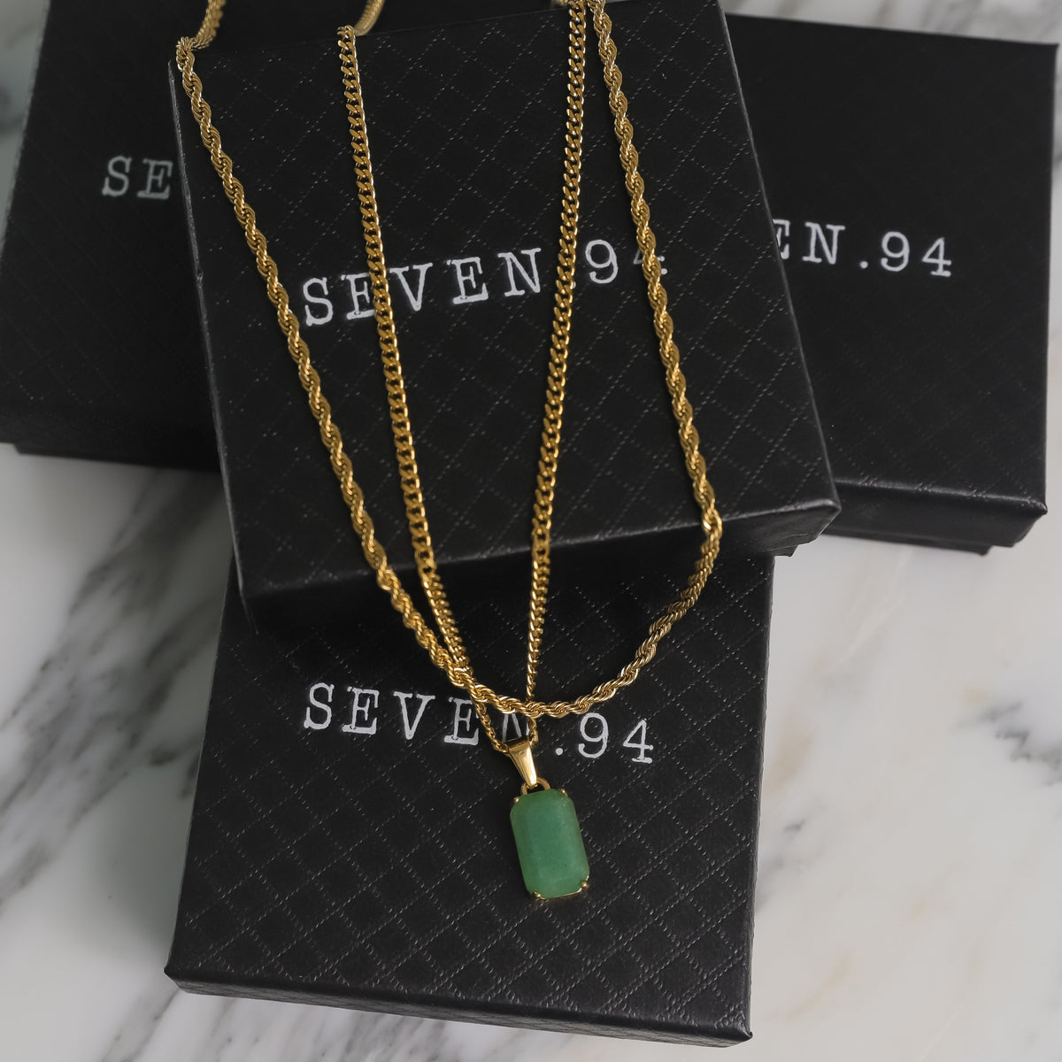 Gold-tone layered chain necklace set with green square stone pendant