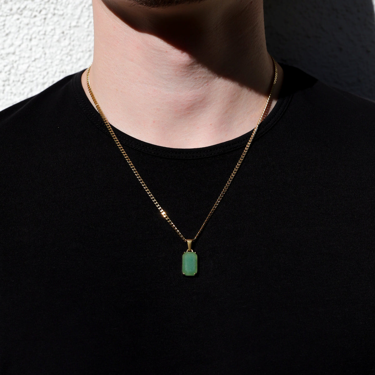Gold chain necklace with small green rectangular stone pendant on wearer